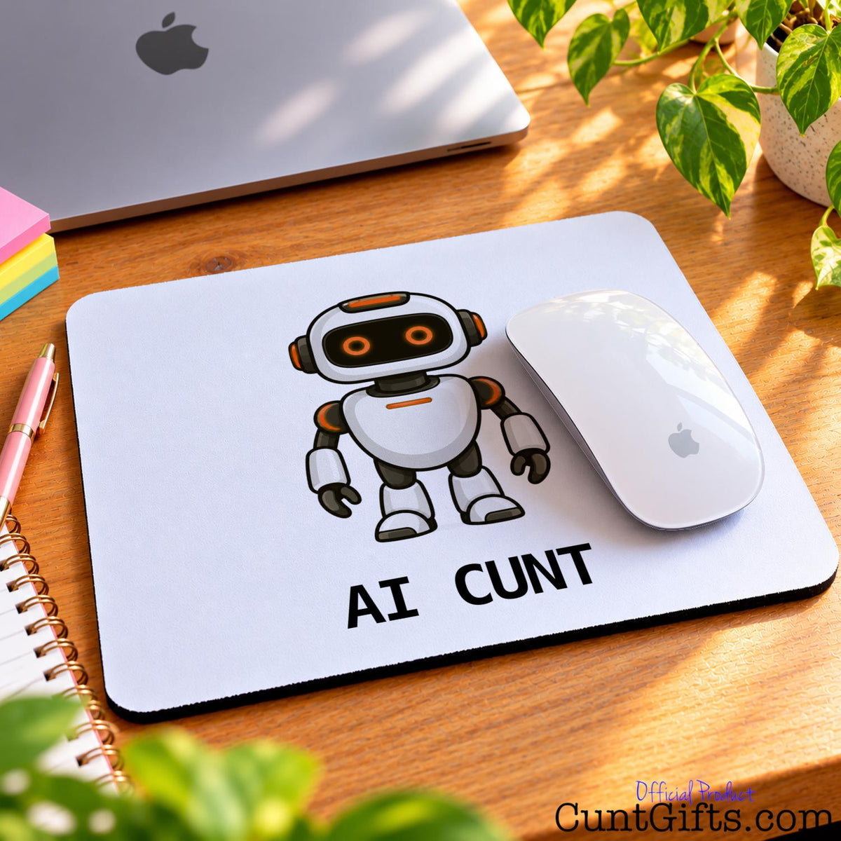 Funny AI Cunt mouse mat featuring a cartoon robot beside a white Apple mouse, computer and green plants.