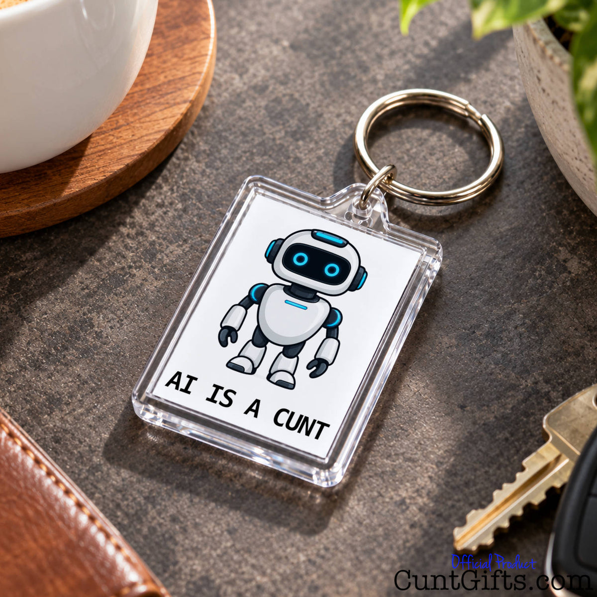 Close-up of an AI Is a Cunt acrylic keyring featuring a blue-eyed robot design resting beside a set of keys.