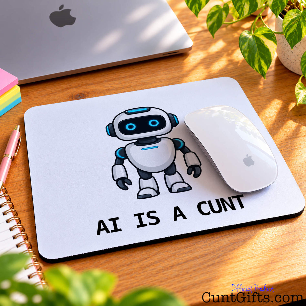 AI Is a Cunt novelty mouse mat featuring a cartoon robot on a wooden desk beside an Apple computer and white mouse.