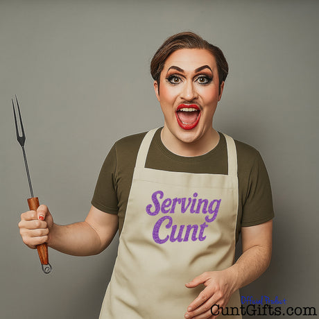 Person wearing a 'Serving Cunt' apron holding a fork and knife against a grey background