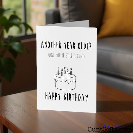 Another year older and you're still a cunt Birthday card on a table.