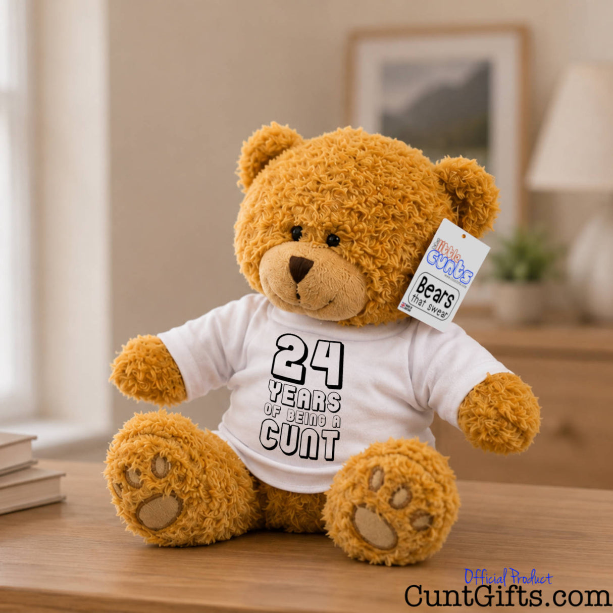 ANY Years of Being a Cunt personalised plush teddy bear sitting on bedroom sideboard with picture frame on wall in background and plant on chest of drawers.