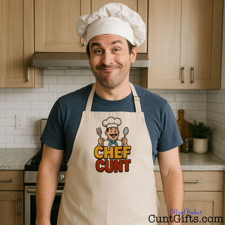 Person wearing a Chef Cunt apron with hat on laghing in a kitchen setting