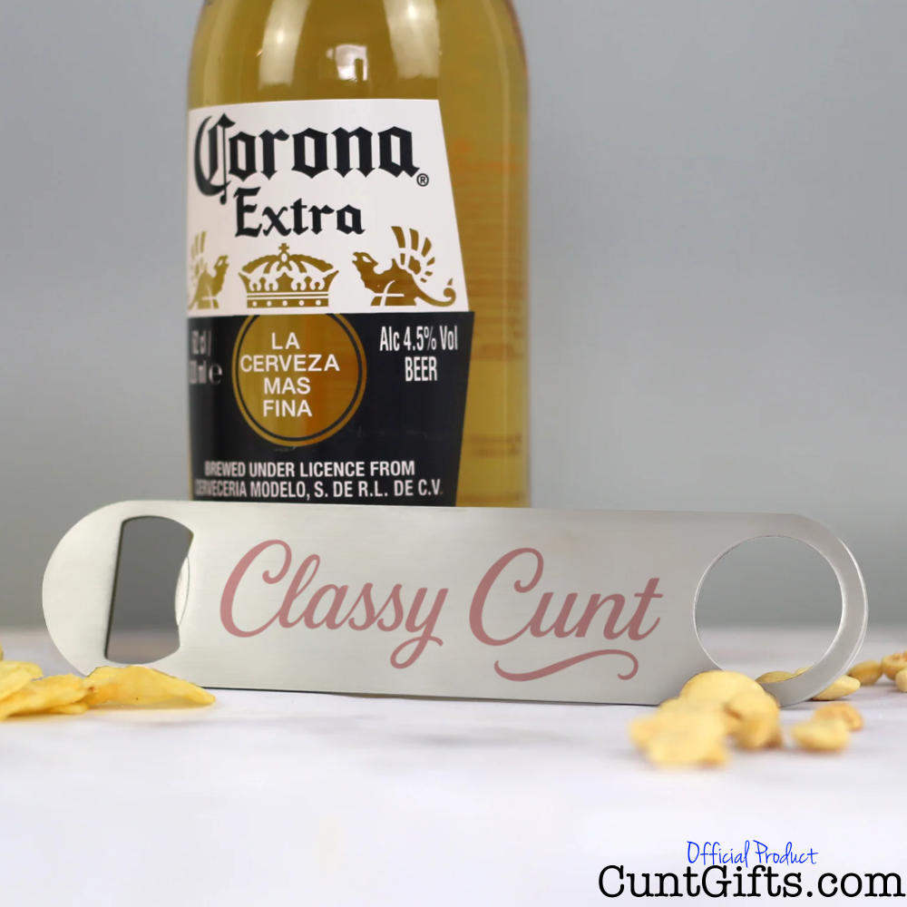 Classy Cunt bottle opener next to beer and nuts.