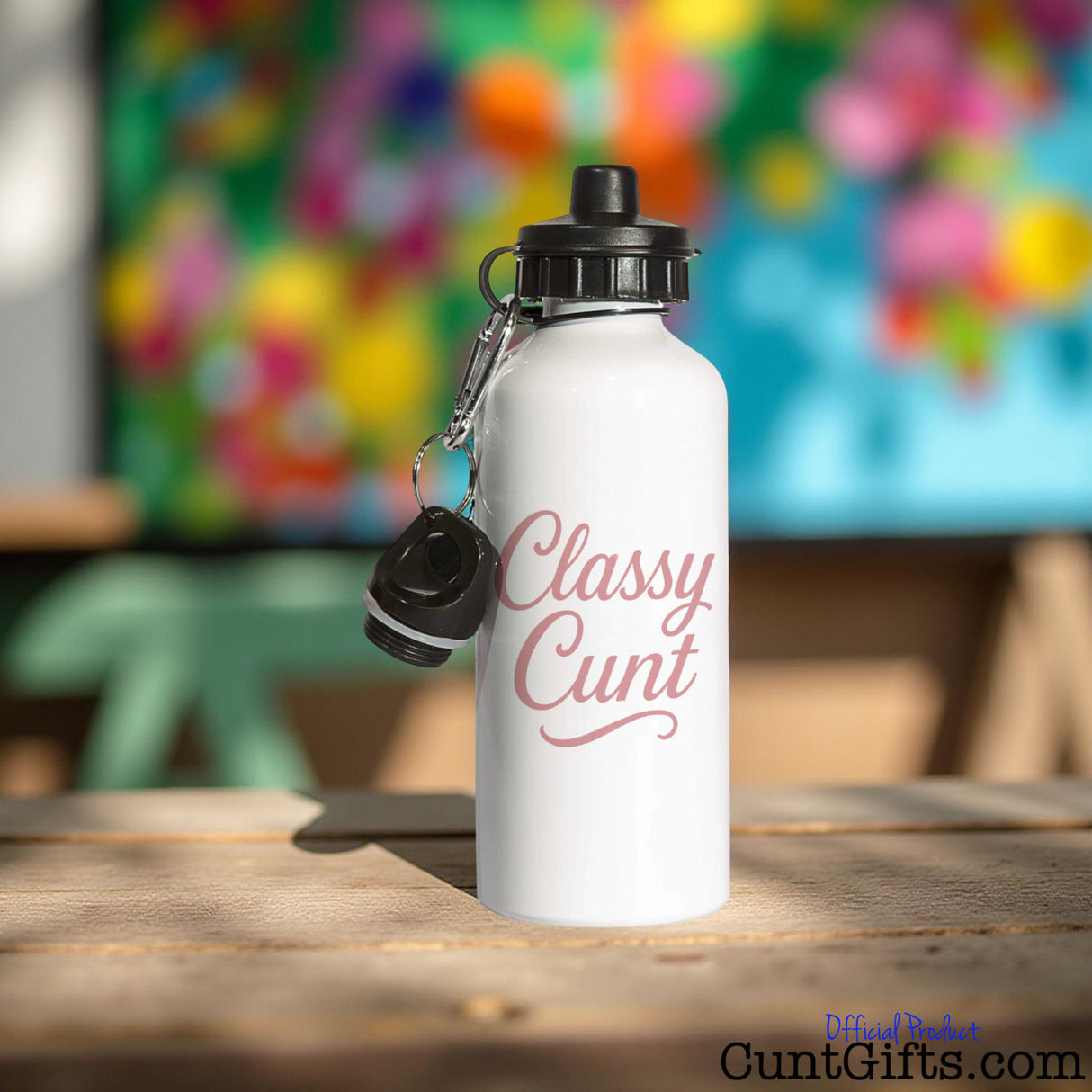 White water bottle with 'Classy Cunt' text on a wooden table with a colorful blurred background.