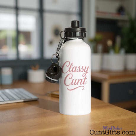 White water bottle with 'Classy Cunt' design on a desk at a workplace by a laptop computer.