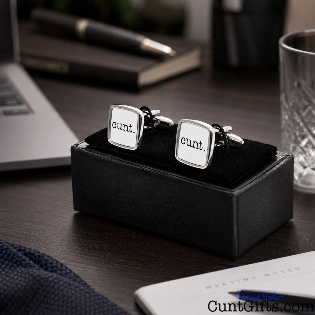 Cunt Cufflinks - white design in presentation gift box on office tablle next to laptop, pen and glass.