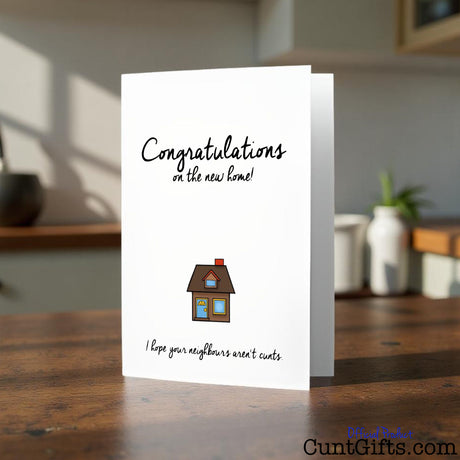 Congratulations on the new home greeting cunt card with a house illustration on a wooden surface
