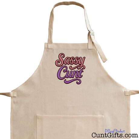 Close-up of a linen apron with 'Sassy Cunt' text on a white background