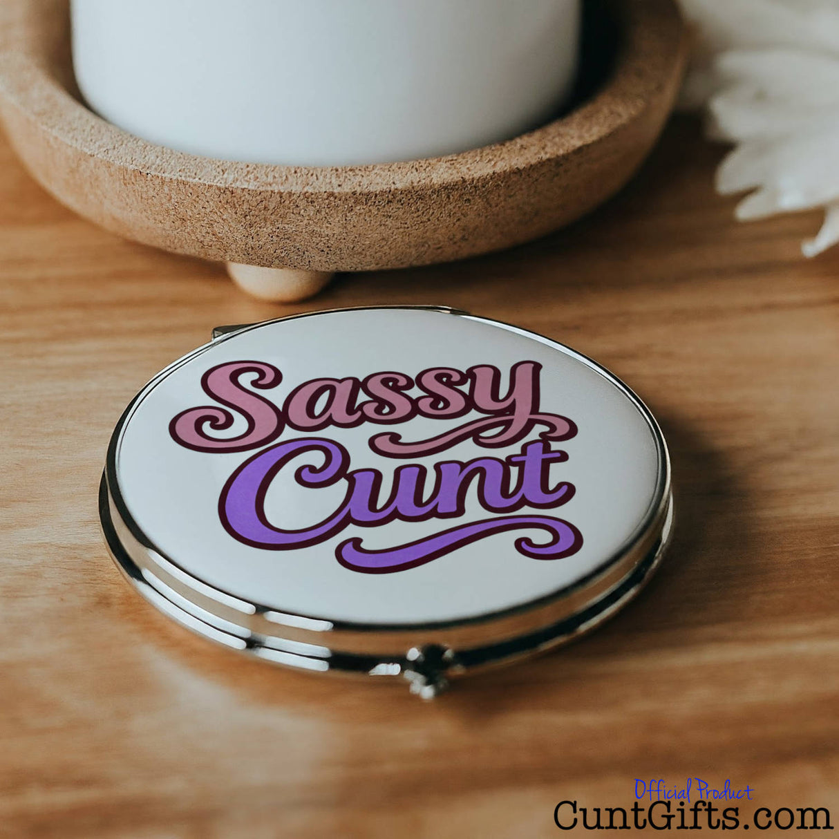 Compact mirror with 'Sassy Cunt' text on a wooden surface