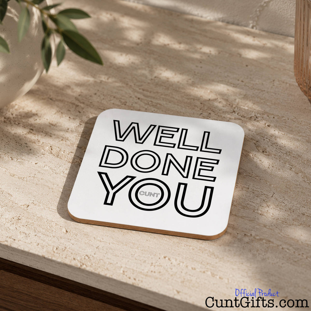 Well Done You Cunt - Drinks coaster on stone worktop next to plant.