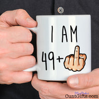I am any age + Fuck You Mug held by man in black shirt