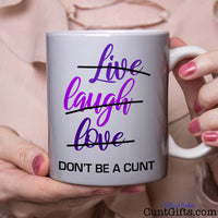 Live Laugh Love Don't be a cunt - mug held by woman in pink blouse