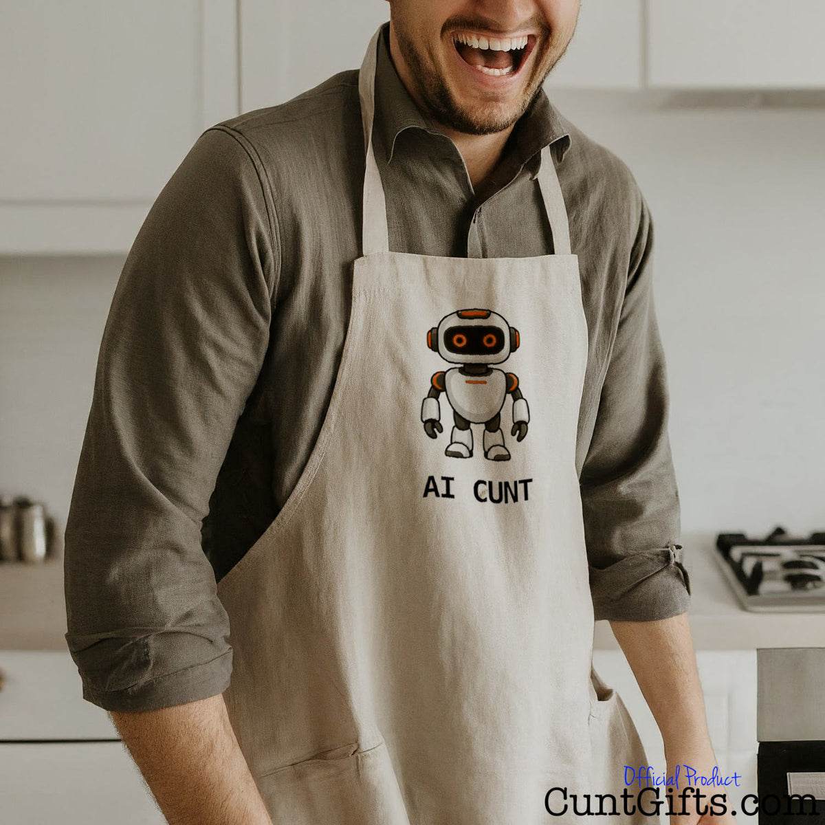 Man wearing a funny AI Cunt apron featuring an orange-eyed cartoon robot design in a kitchen.