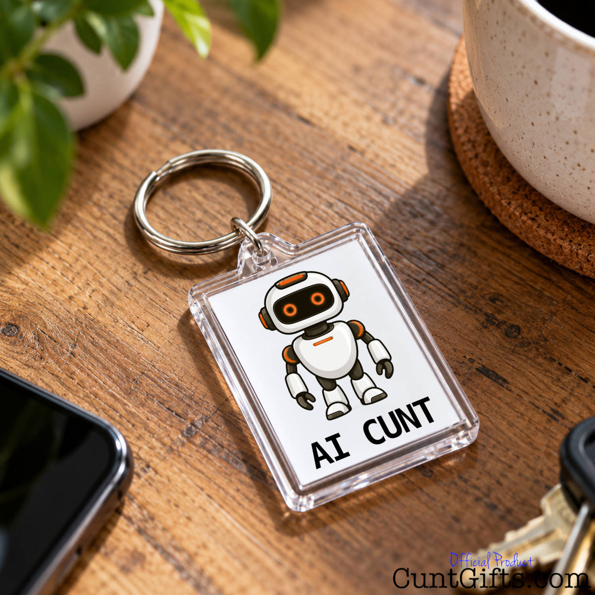 Close-up of an AI Cunt acrylic keyring featuring an orange-eyed robot design resting on a wooden table.