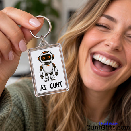Smiling woman holding up an AI Cunt novelty keyring featuring a cheeky cartoon robot and rude slogan.