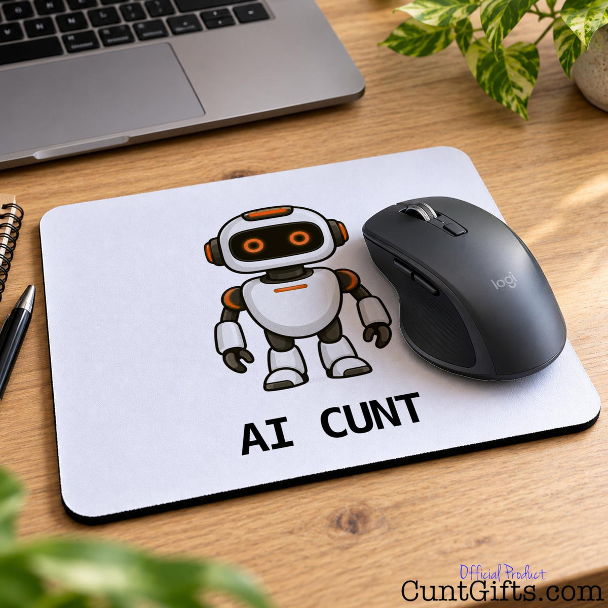 AI Cunt novelty mouse mat featuring an orange-eyed robot design with a black wireless mouse on a wooden office desk.