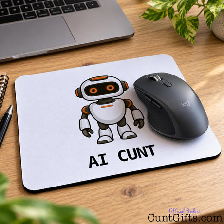 AI Cunt novelty mouse mat featuring an orange-eyed robot design with a black wireless mouse on a wooden office desk.