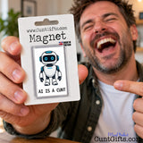 Laughing man holding up a funny AI Is a Cunt fridge magnet in its branded packaging.