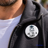 AI Is a Cunt novelty pin badge attached to dark clothing, showing the 44mm badge in a lifestyle setting.