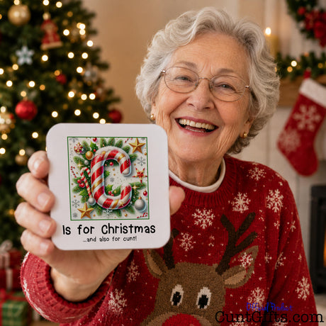 C is for Christmas and also for cunt - drink coaster held by laughing elderly woman in Christmas jumper by tree with fairy lights.