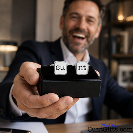Cunt Cufflinks - CU and NT white design in presentation gift box. Held by man in suit laughing at desk.