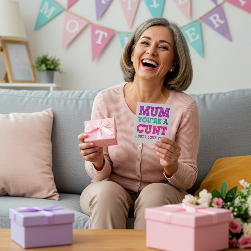 Mum holding Mother's Day cunt card and gifts, sitting on a couch with a pink banner on the background wall.
