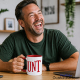 UNT Mug in red with man laughing at desk with laptop.