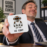 Smiling man in a suit holding up a funny AI Cunt drink coaster featuring an orange-eyed robot design.