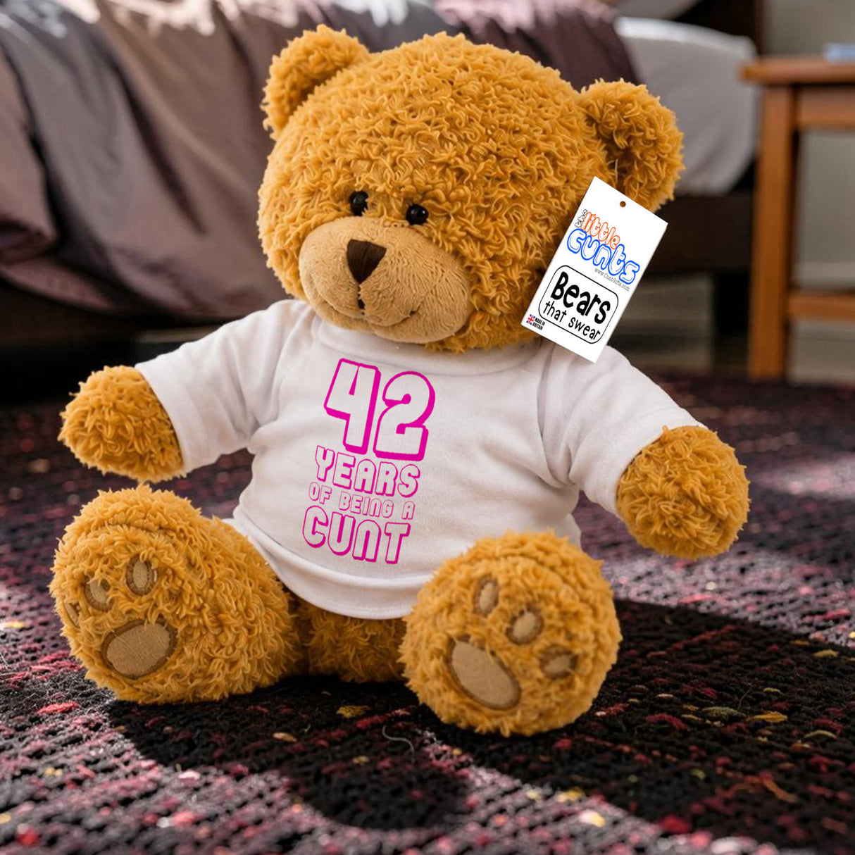 ANY Years of Being a Cunt - personalised birthday teddy bear with pink writing sitting on rug in bedroom next to bed and table.