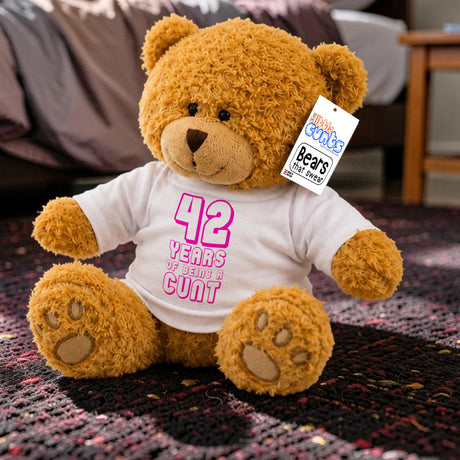 ANY Years of Being a Cunt - personalised birthday teddy bear with pink writing sitting on rug in bedroom next to bed and table.
