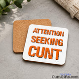 Attention Seeking Cunt - Drink Coaster showing both sides with cork backing on marble table by folded rub and plant.