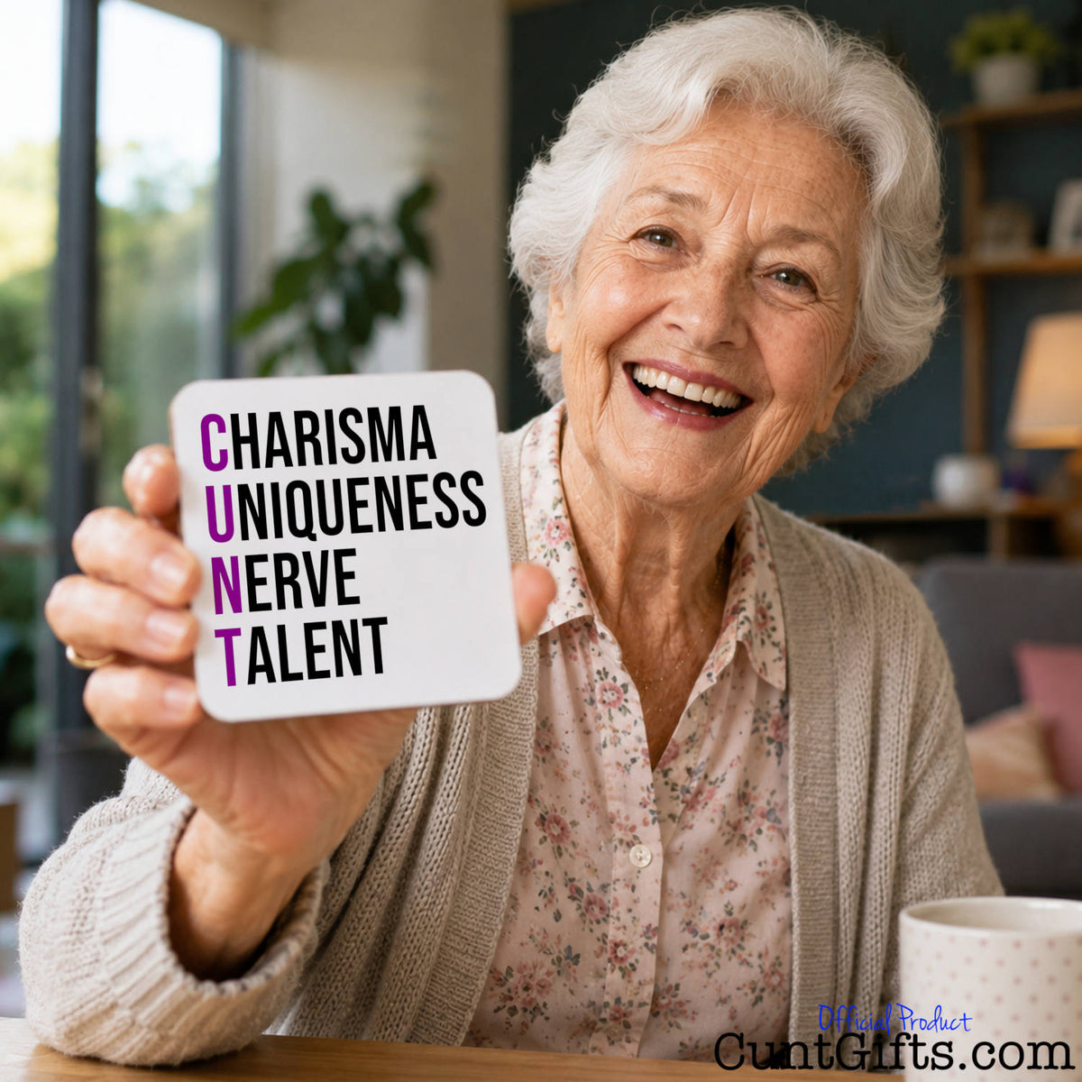 An elderly woman with white hair smiles while holding up a white square drinks coaster that reads 'CHARISMA UNIQUENESS NERVE TALENT' CUNT design.