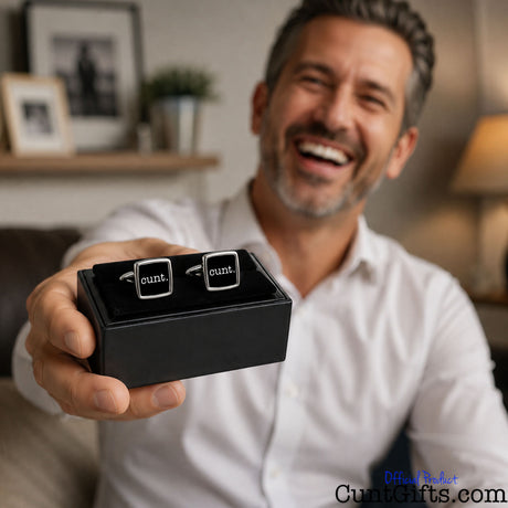 Cunt Cufflinks - Black design with laughing man with stubble in white shirt in living room. Pictures and table lamp is in background.