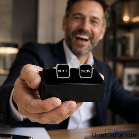 Cunt Cufflinks - black design in presentation gift box held by man in suit and white shirt in office.