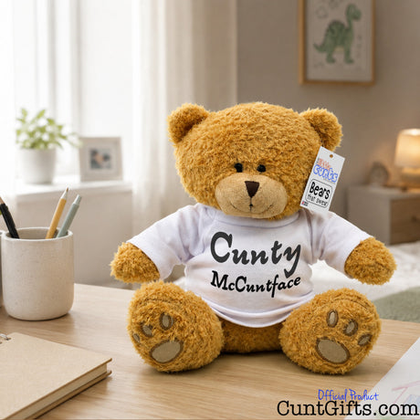 Cunty McCuntface soft toy teddy bear plush on bedroom table by pen pot and notepad