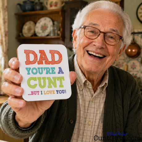 An older man smiling and holding up a square white gift card that reads "Dad You're A Cunt But I Love You".