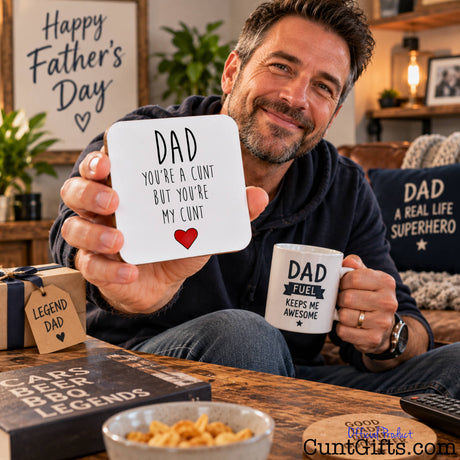Dad You're a Cunt But You're My Cunt - Drink coaster hled by dad on Father's Day in lounge by coffee table and sofa.