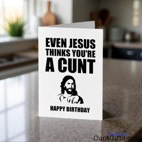 Even Jesus thinks you're a cunt birthday card on a kitchen counter with a blurred background