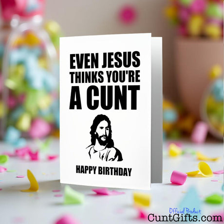 Even Jesus thinks you're a cunt birthday card placed on a colourful confetti-covered surface