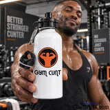 A man in a gym holding a white water bottle with a black cap and a black-and-orange Gym Cunt logo on the front.