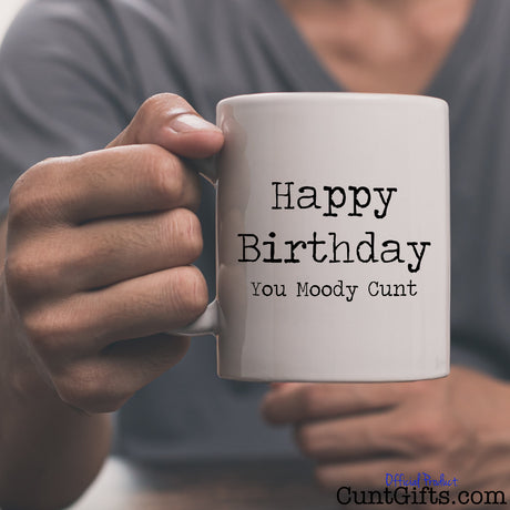 Happy Birthday You Moody Cunt - Mug held by man in grey tee shirt