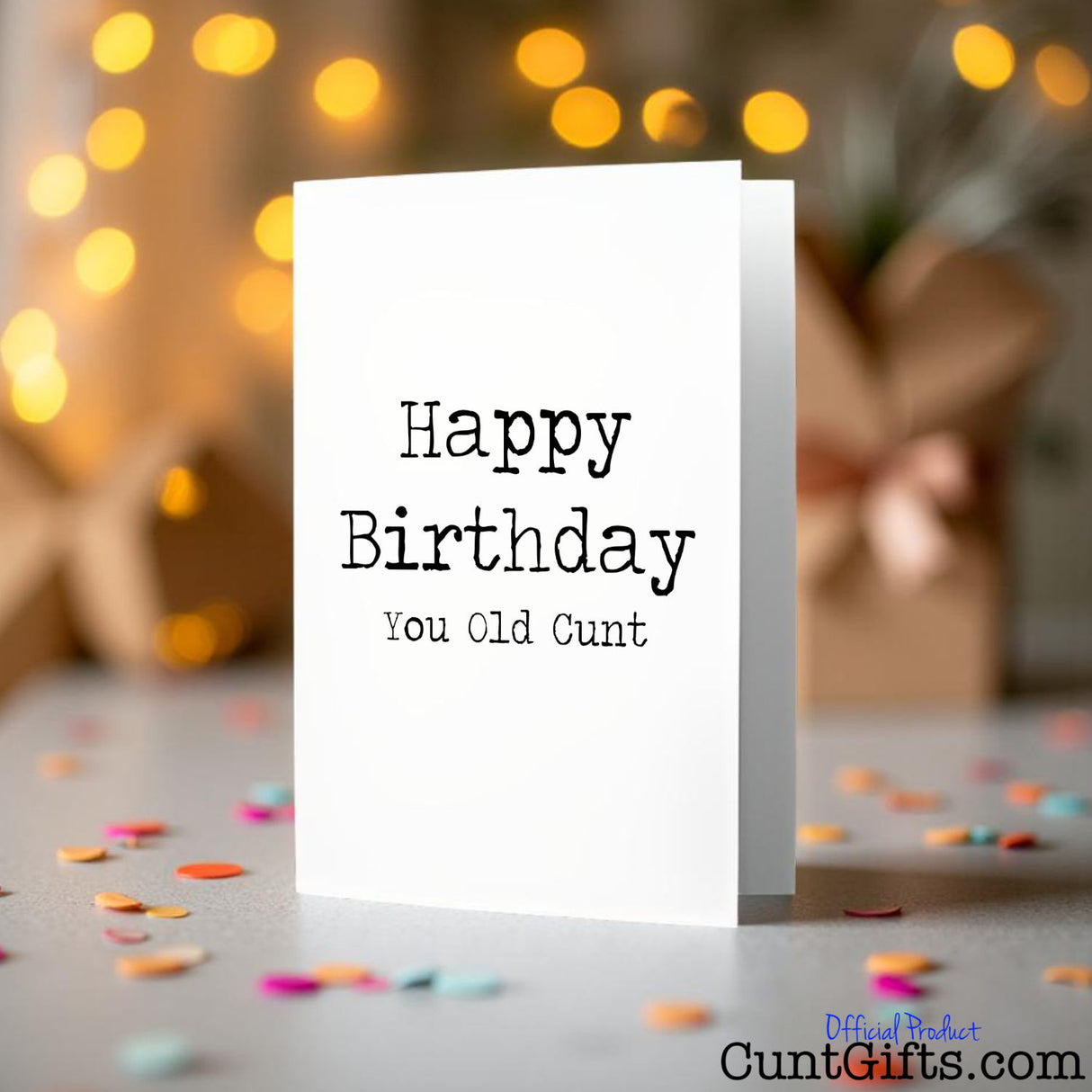 Happy Birthday You Old Cunt birthday card on a blurred background with lights and confetti.