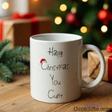 Happy Christmas You Cunt Mug by gifts and  tree with fairy lights.