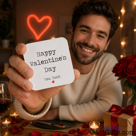 Happy Valentines Day You Cunt - drink coaster held my bearded man in room with roses and heart light.