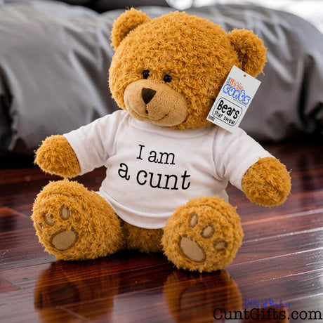 I am a cunt - Teddy Bear plush with golden brown fur on polished wooden floor in bedroom.