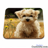 A rectangular mouse pad with rounded corners featuring a printed photo of a fluffy cream-colored dog sitting in grass with yellow flowers and the word cunt.