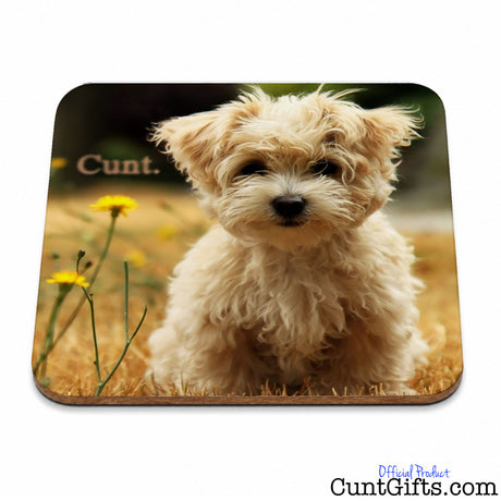 A rectangular mouse pad with rounded corners featuring a printed photo of a fluffy cream-colored dog sitting in grass with yellow flowers and the word cunt.