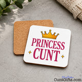 Princess Cunt Drink Coaster on marble with cloth and leaves