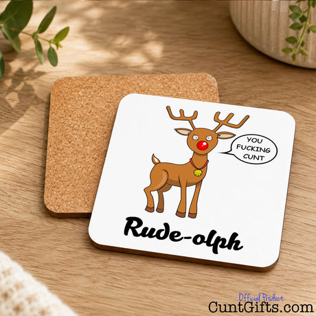 Rude-olph - You fucking cunt. Christmas drink coaster showing both sides on wooden table next to plants.